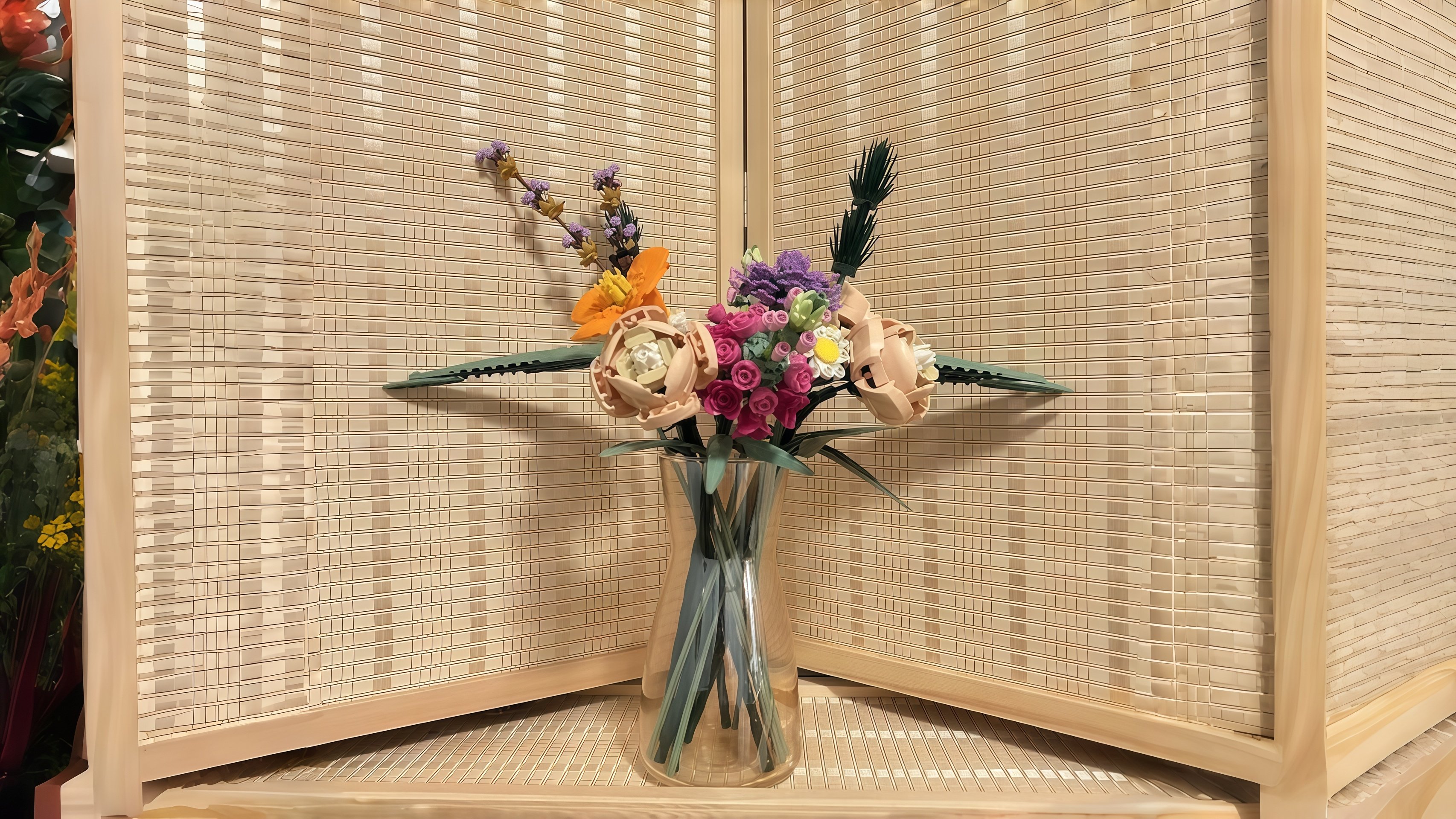 Clear glass flower vase with realistic faux white roses and eucalyptus on a wooden table, elegant centerpiece that looks fresh without maintenance